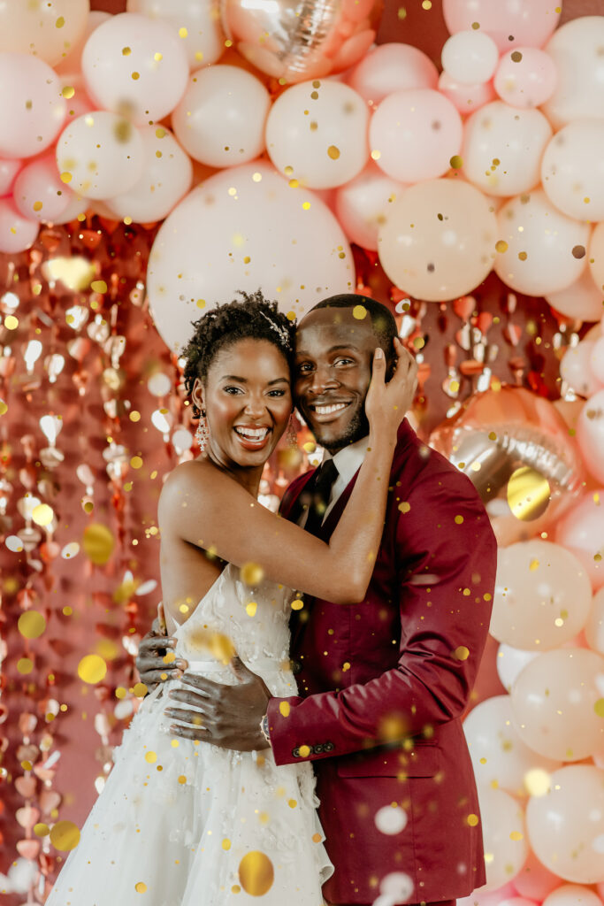 Couple posing amidst falling gold confetti in playful and romantic valentine's shoot.