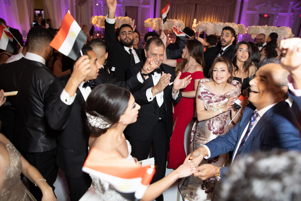 Wedding guests dance holding Egyptian flags at classic luxurious wedding in Florida.