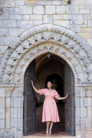 Model posing under Spanish Monastery archer in blooming Spring wedding styled shoot.