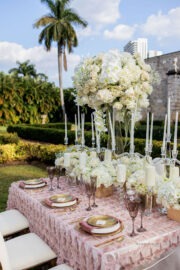 White candles with white and pastel floral arrangements for blooming spring wedding themed tablescape design.