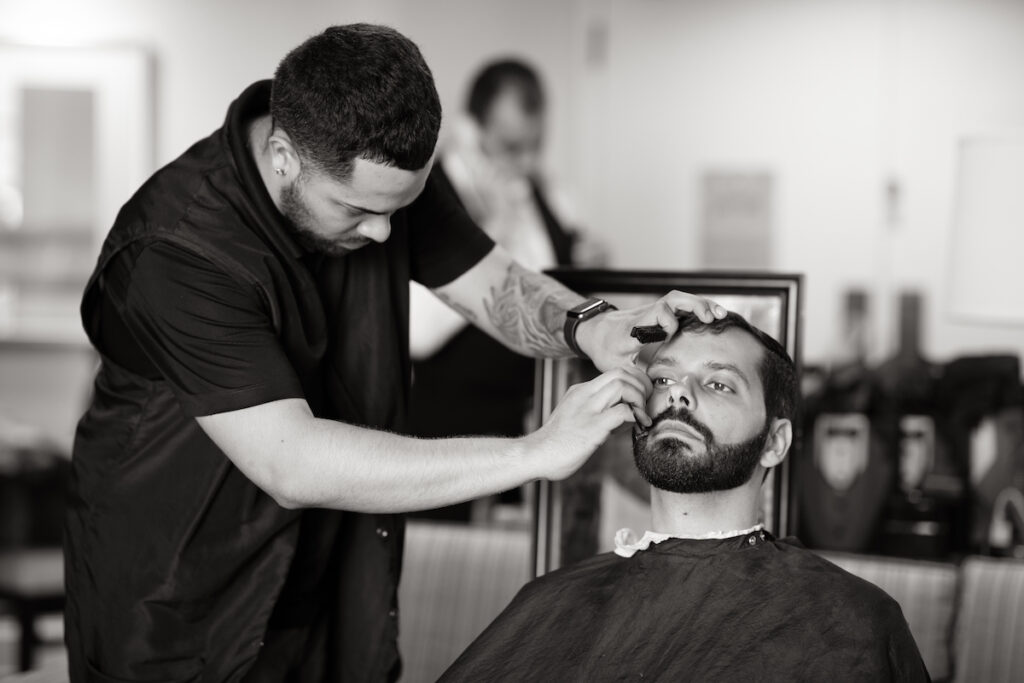 Groom prepares for classic luxurious wedding by getting a shave.