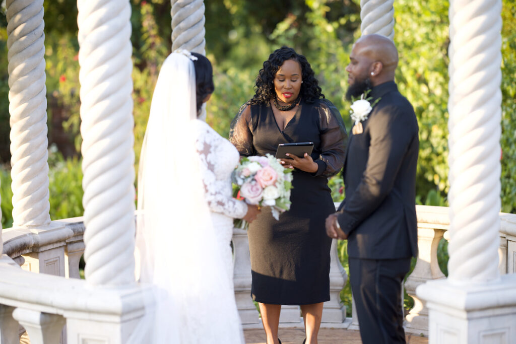 CEO of Just Elope & Love is Blind Officiant, Jennifer Allen, officiating a couple's wedding in a white gazebo