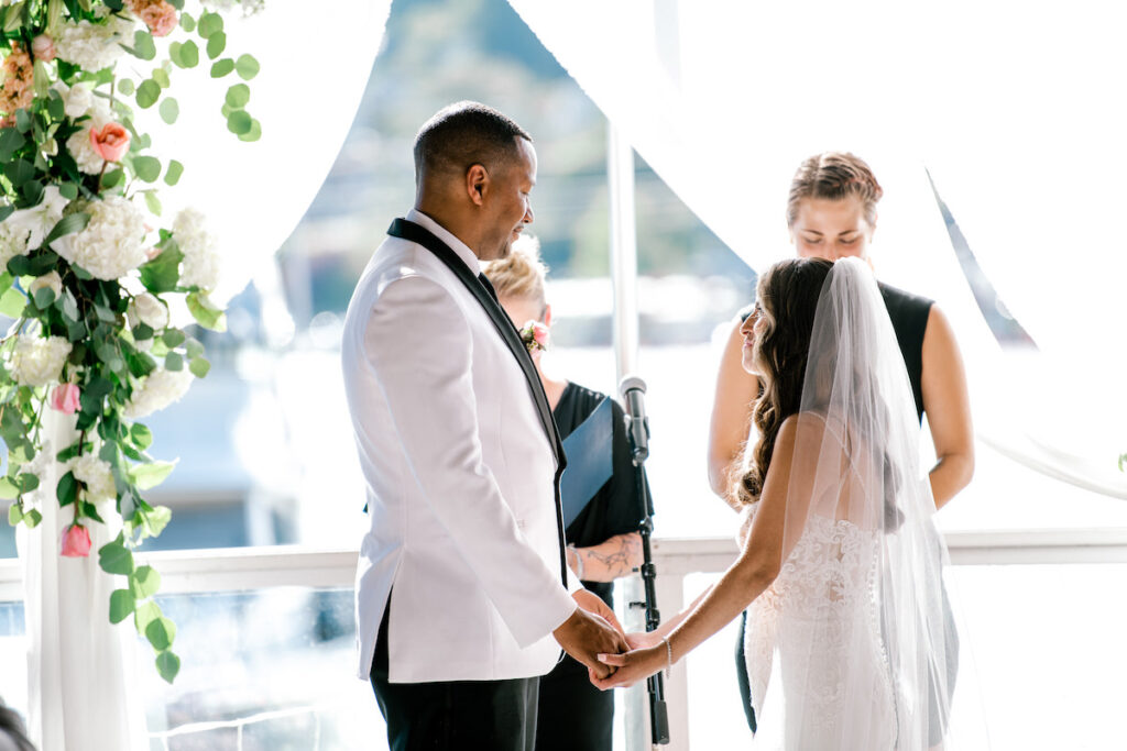 This waterfront wedding at the Tyee Yacht Club in Seattle, WA, features soft pink blooms, pops of red, and a bilingual English/Spanish ceremony.